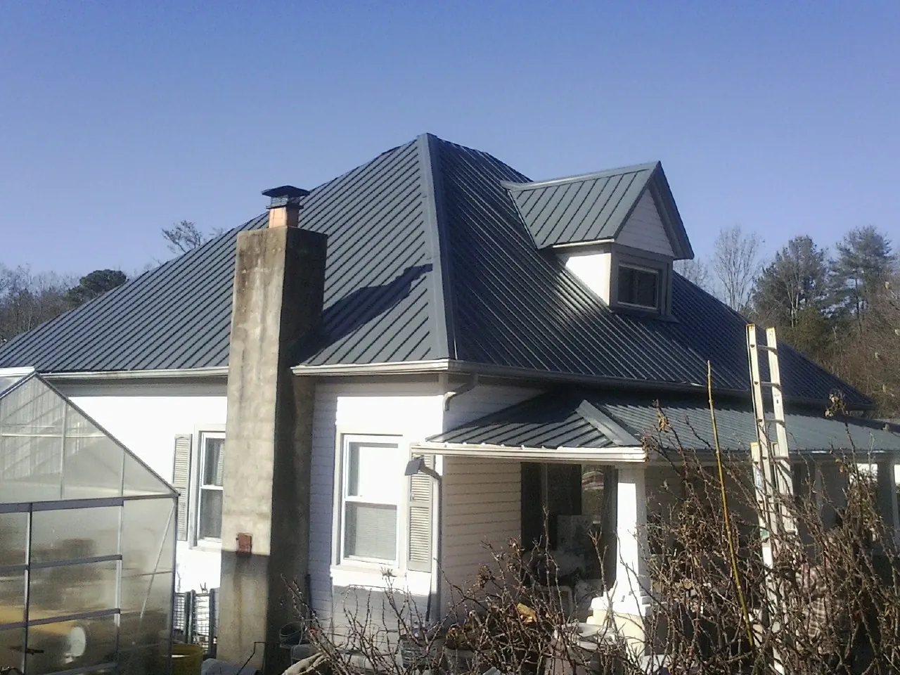 Dark blue standing seam metal roof on a white farmhouse with dormer — Slate & Tile Roof Repair by Roofing Brothers in Meadville
