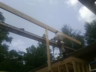 Carpenter setting a ridge beam over a new addition frame — Ice Dam Removal by Roofing Brothers in Meadville