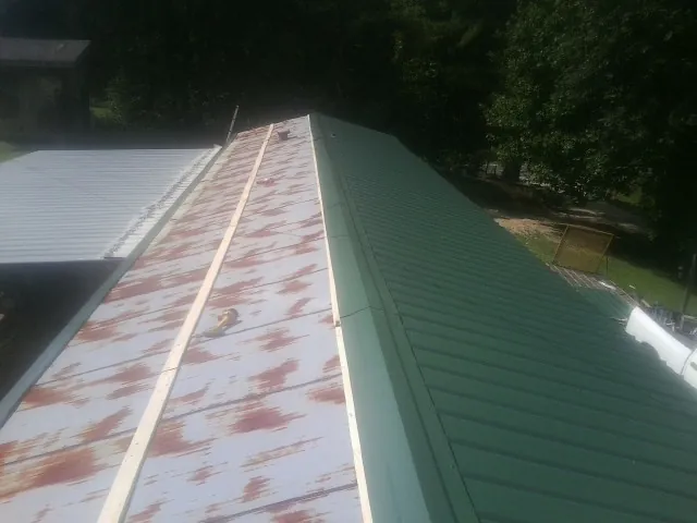 Old rusted panels beside newly installed green metal roofing — Wind Damage Roof Repair by Roofing Brothers in Meadville