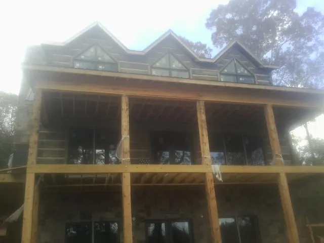 Dormers and porch framing on a large log home under construction — Roof Coating work by our crew in Meadville