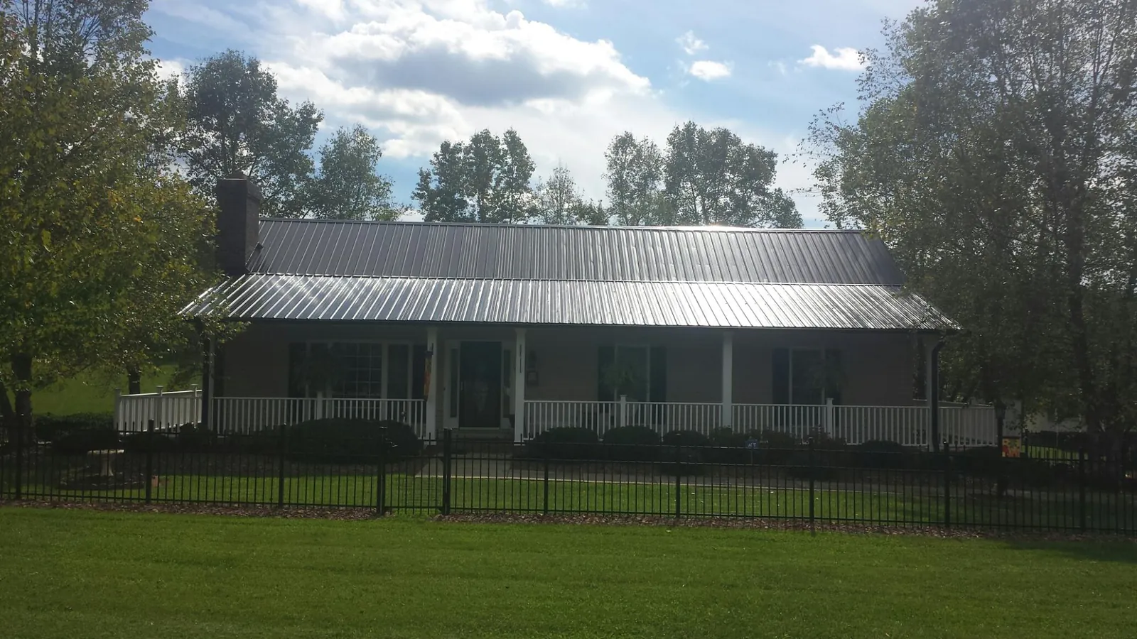 Gray metal roof on a brick ranch with a full width front porch — Gutter Guard Installation work by our crew in Meadville