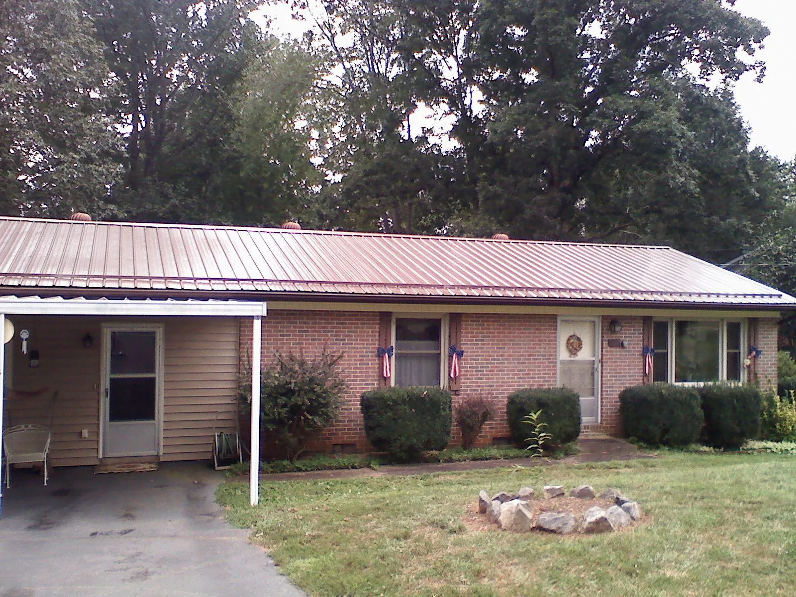 Bronze metal roof and carport on a brick ranch home — Roof Repair work by our crew in Meadville
