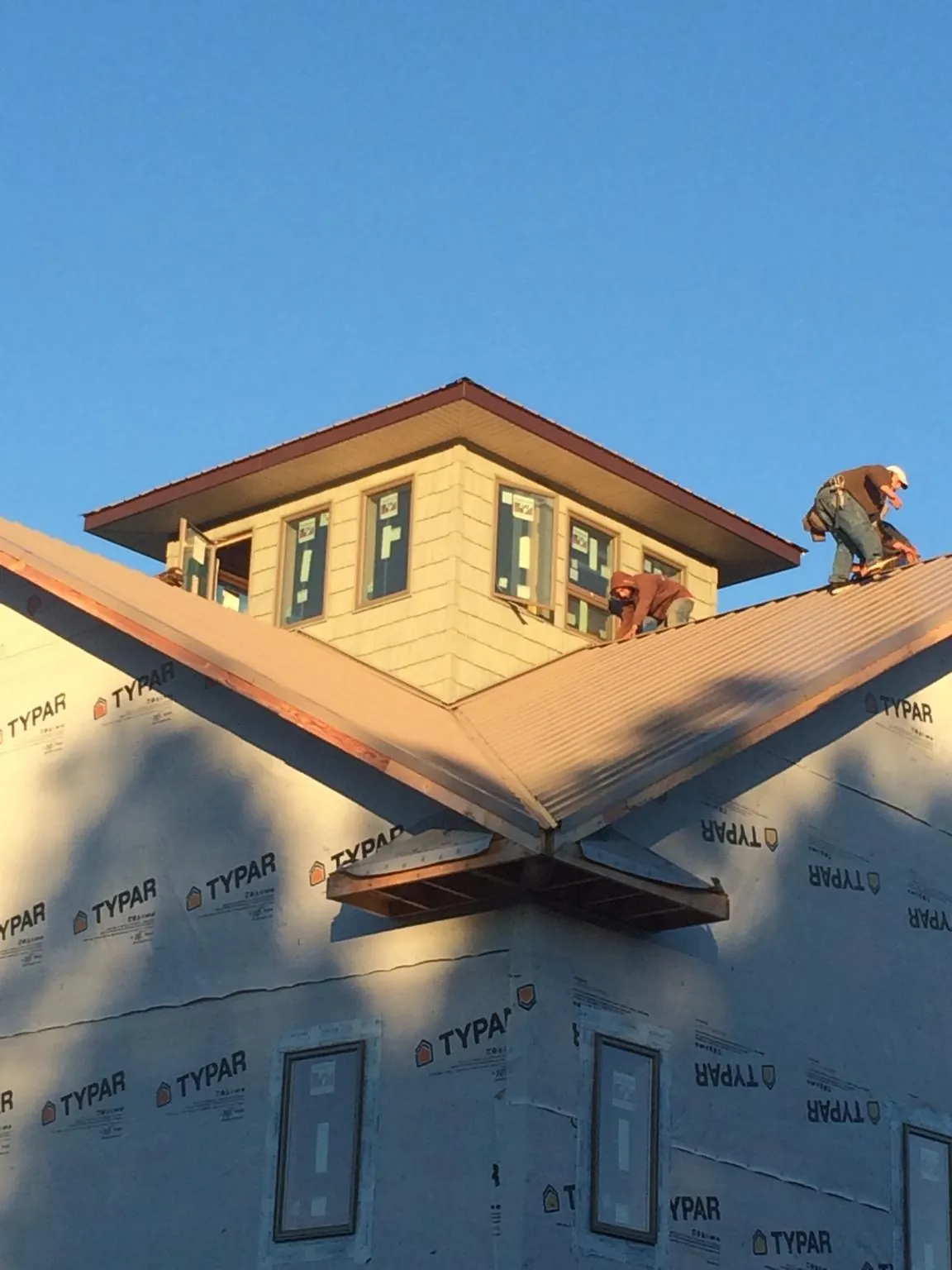 Roofers working around a rooftop cupola on a new metal roof at sunset — Roof Waterproofing in Meadville by Roofing Brothers